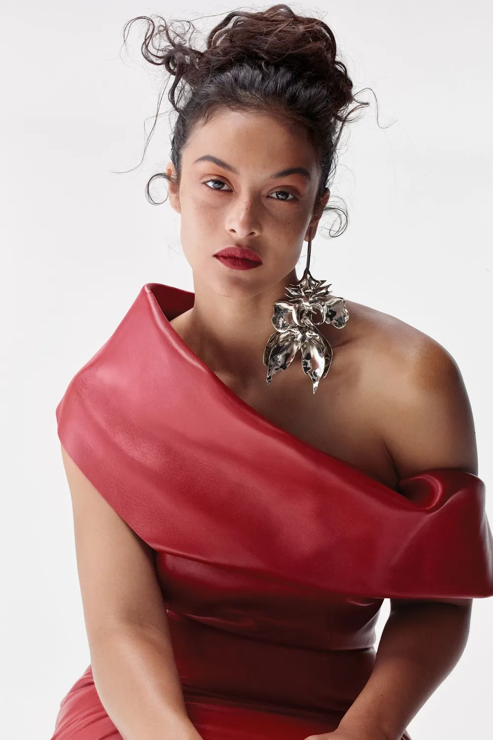 Devyn Garcia wearing a red off-the-shoulder dress and a statement silver floral earring.