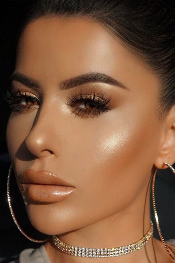 Woman with bronze eye makeup, glowing skin and hoop earrings