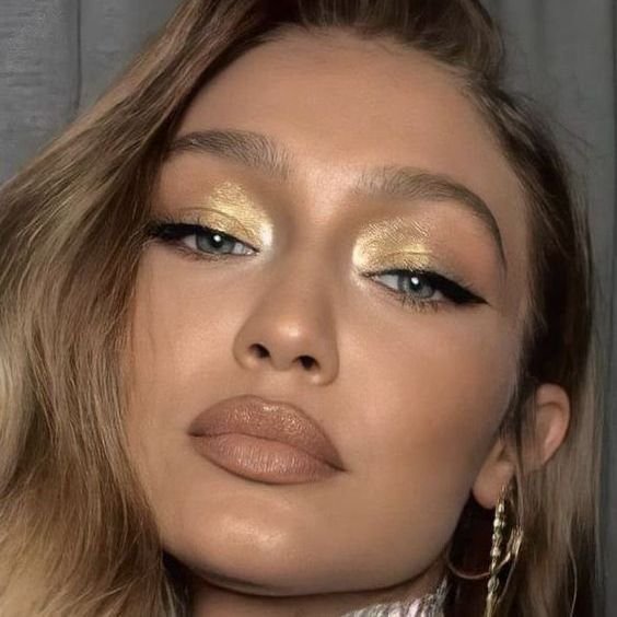 Woman with golden eyeshadow, winged liner and a nude lip
