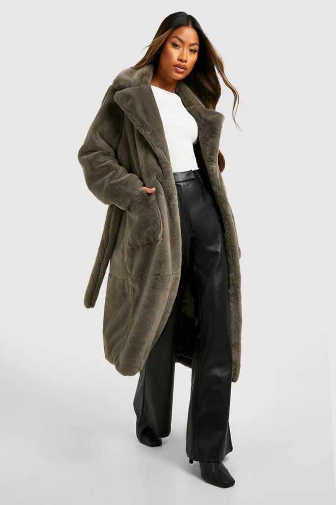 Woman in a belted olive faux fur coat with black trousers