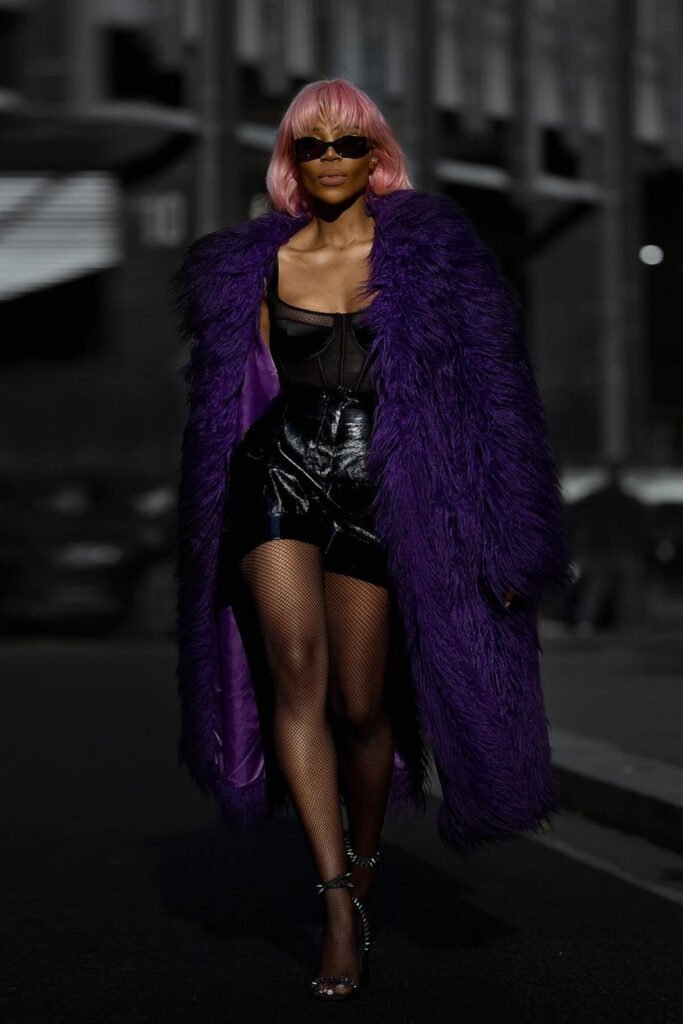 Woman in a purple faux fur coat on a city street at night
