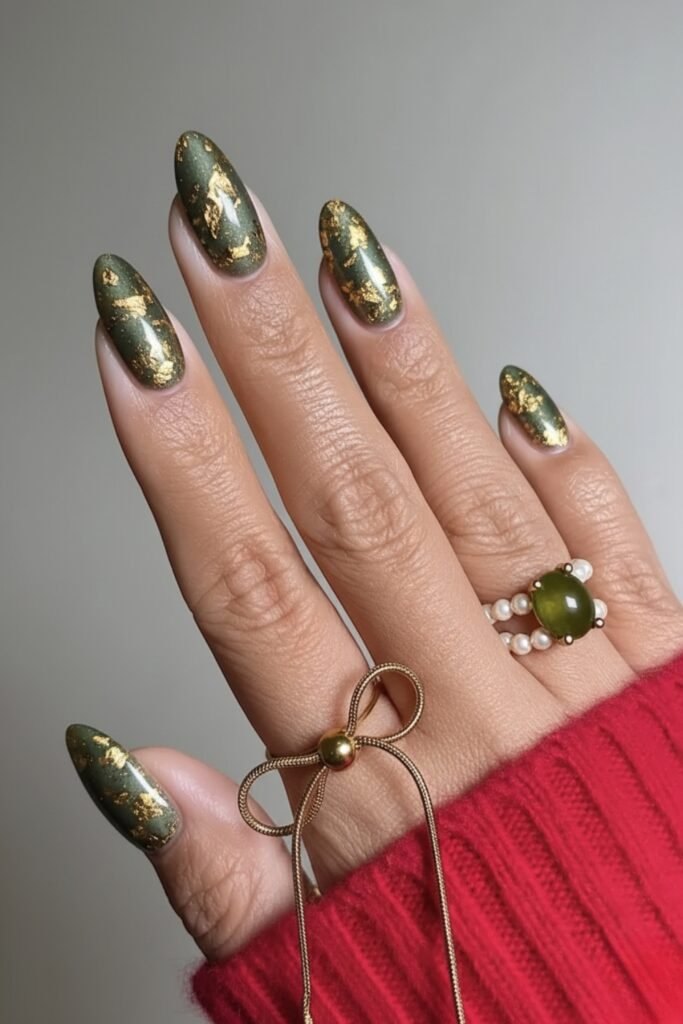 Almond nails in sage green with a glassy chrome finish and gold rings