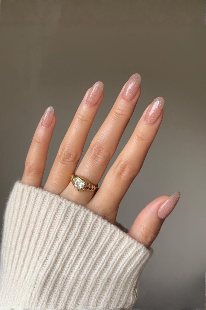 Sparkly nude almond nails with a white knit sleeve