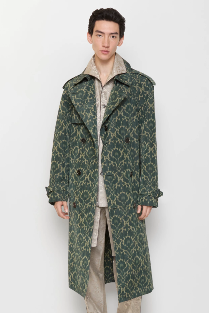 Man in a long green patterned trench coat over light trousers