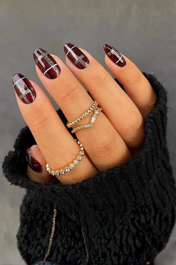 Short burgundy plaid nails with gold rings and a black sweater