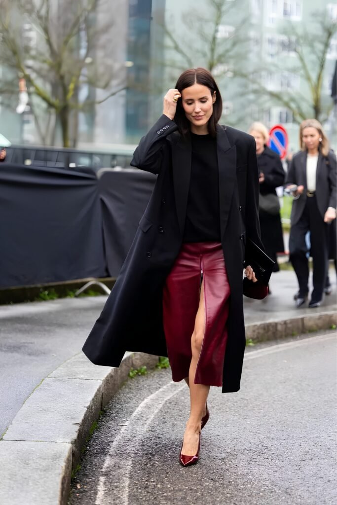 Woman in a cherry red midi skirt with a long black coat