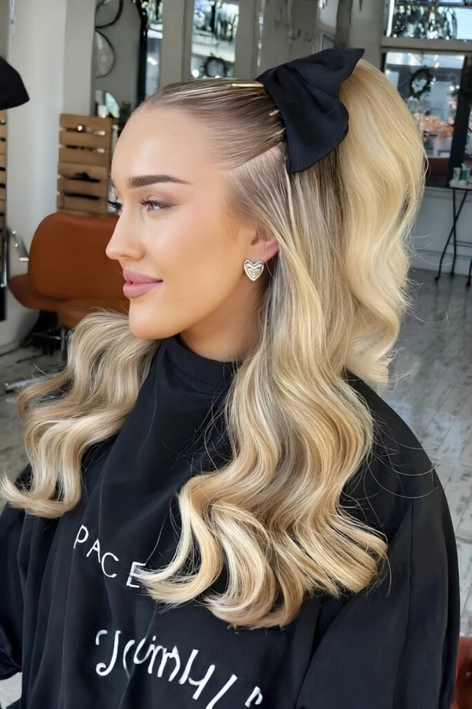 Side view of a half-up curly ponytail with a black bow