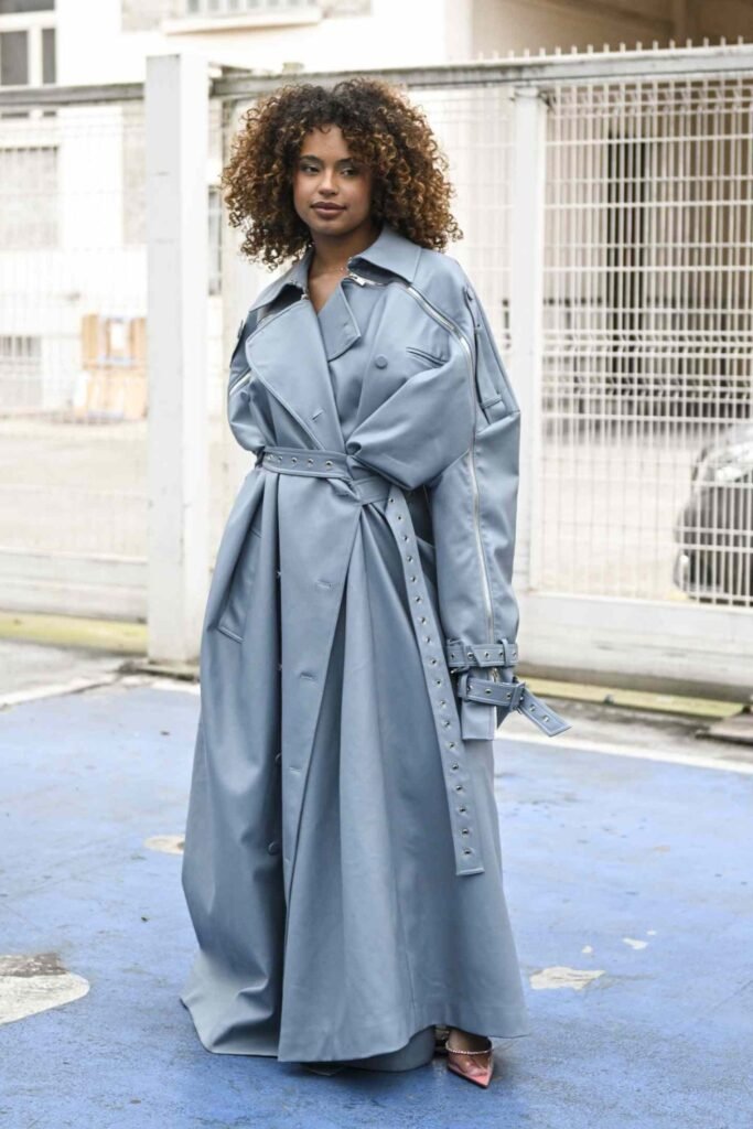 Woman in a light blue belted trench coat on a city street