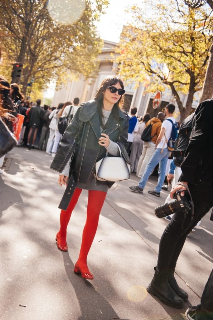 Woman in red tights and red ballet pumps with a dark coat