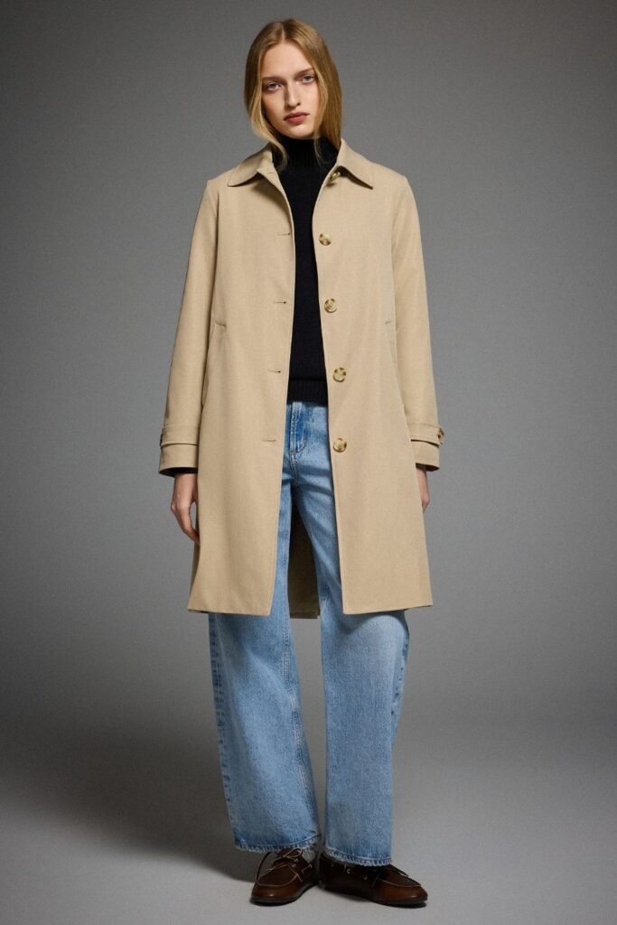Woman in a single-breasted beige trench coat with a black top and jeans