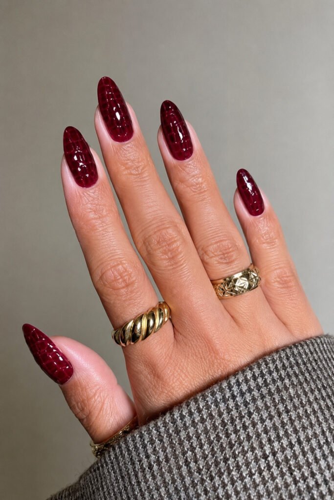 Dark cherry mocha almond nails worn with gold rings