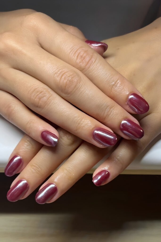Short glossy nails in a shimmering cherry mocha chrome finish