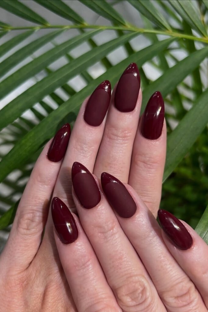 Deep cherry mocha almond nails photographed against a palm leaf