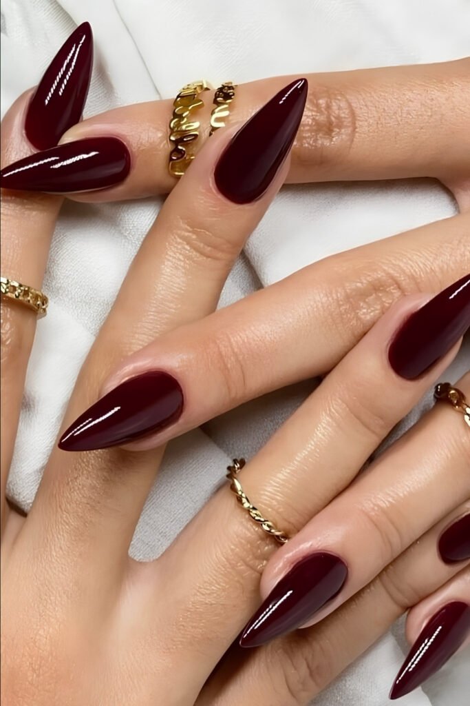 Long glossy cherry wine almond nails with gold rings
