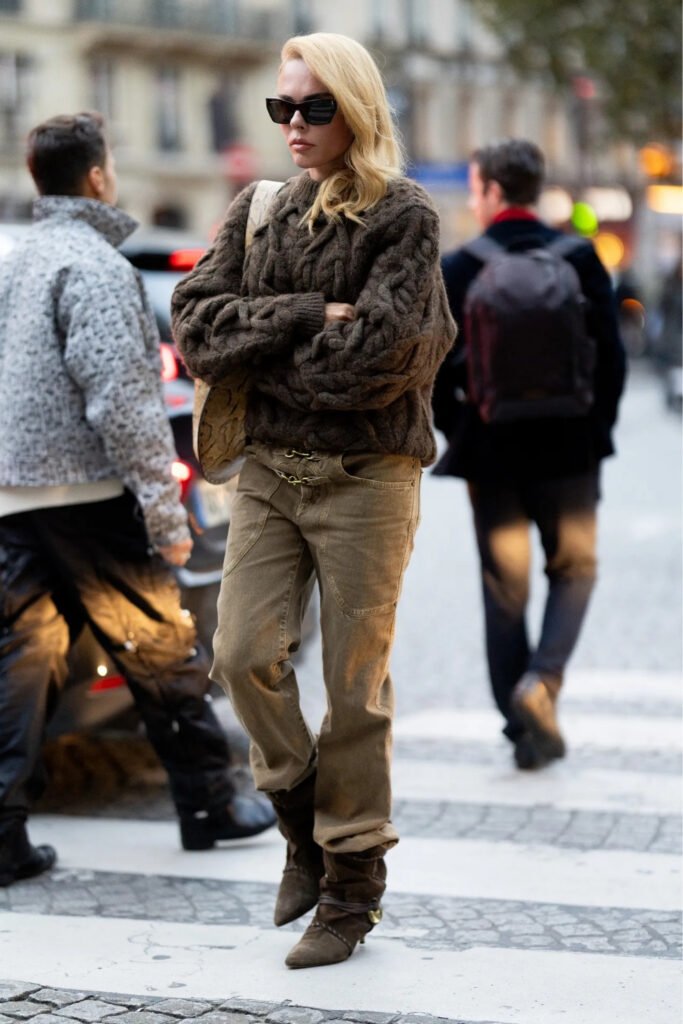 Woman in a chunky knit with cord trousers and boots crossing a street