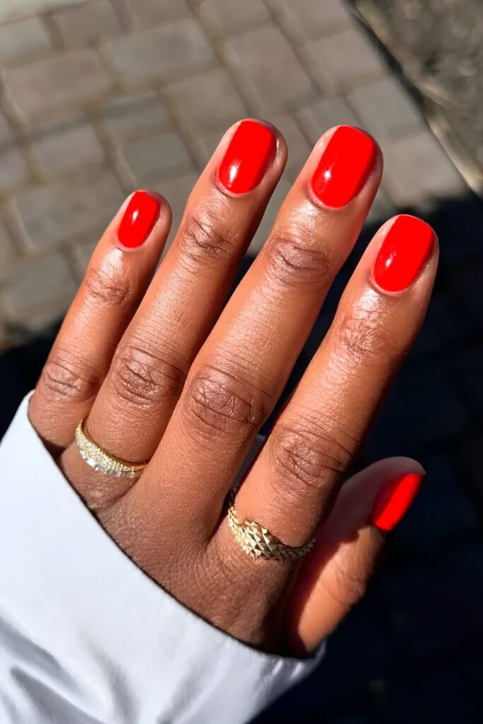 Long almond nails in bright solid cherry red with gold rings