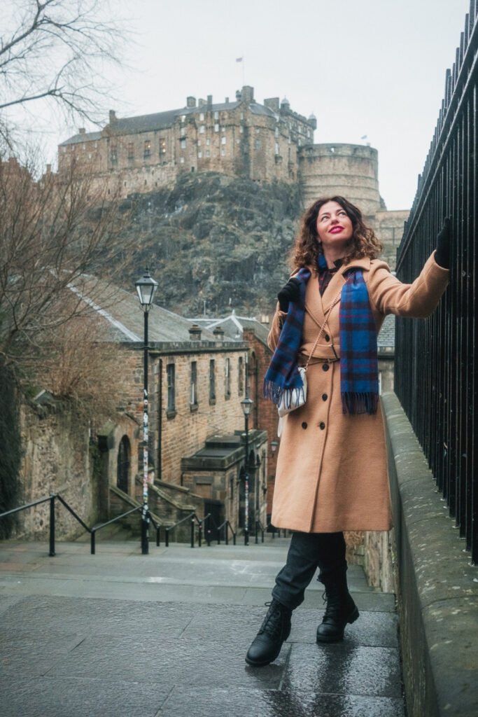 Woman in a camel coat with Edinburgh Castle in the background