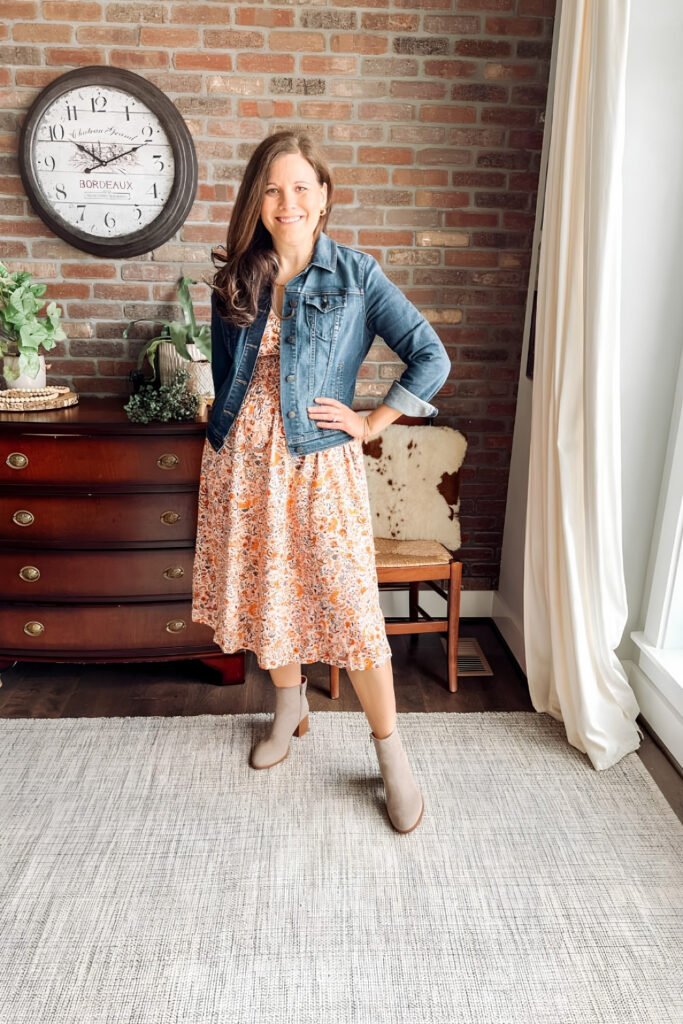 Woman in a floral midi dress with a denim jacket and ankle boots