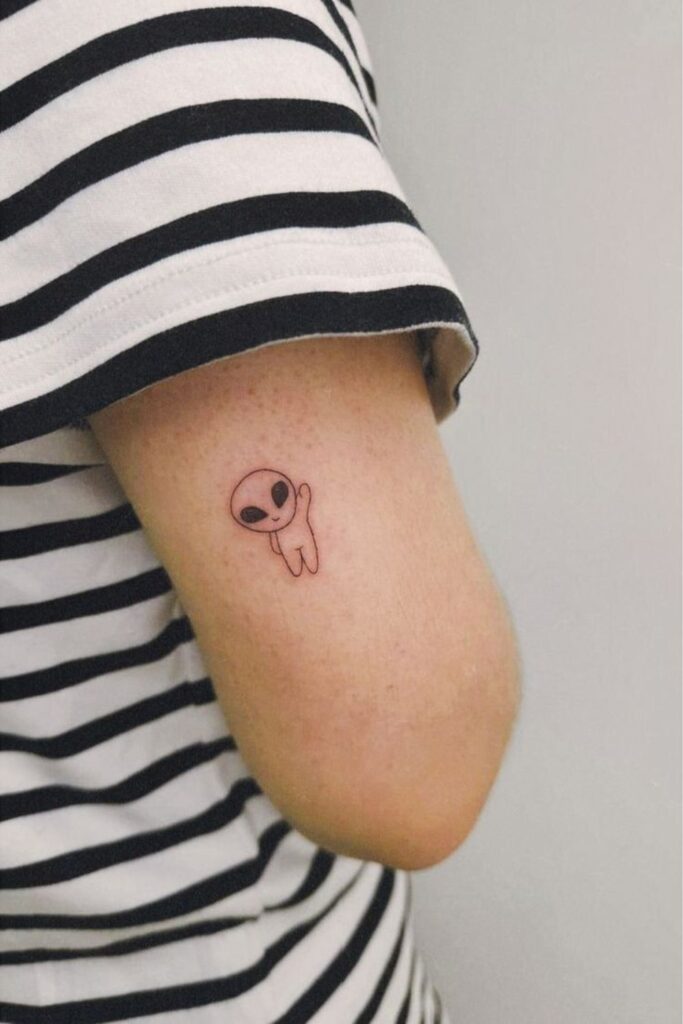 Tiny alien head tattoo on a man