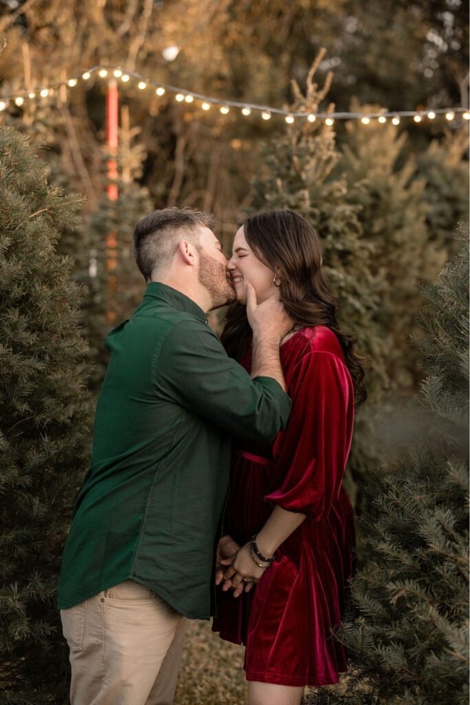 Couple in a forest green shirt and burgundy dress under string lights