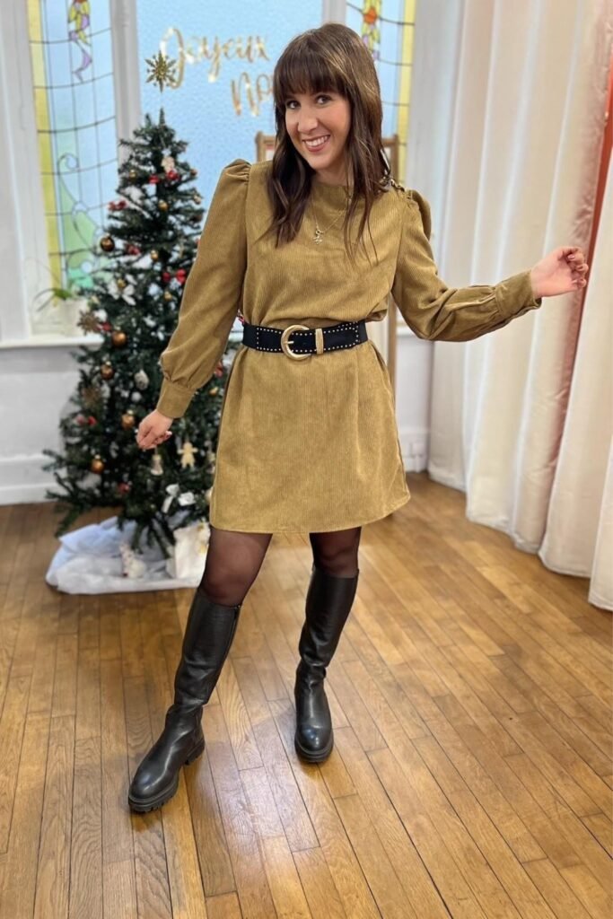 Woman in a mustard corduroy shirt dress with a wide belt and knee-high boots