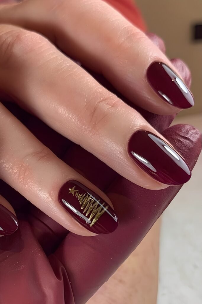 Short wine red nails with one gold-detailed accent nail