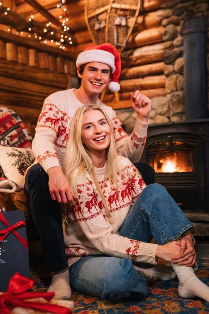 Couple in matching red and white knits by a cabin fireplace