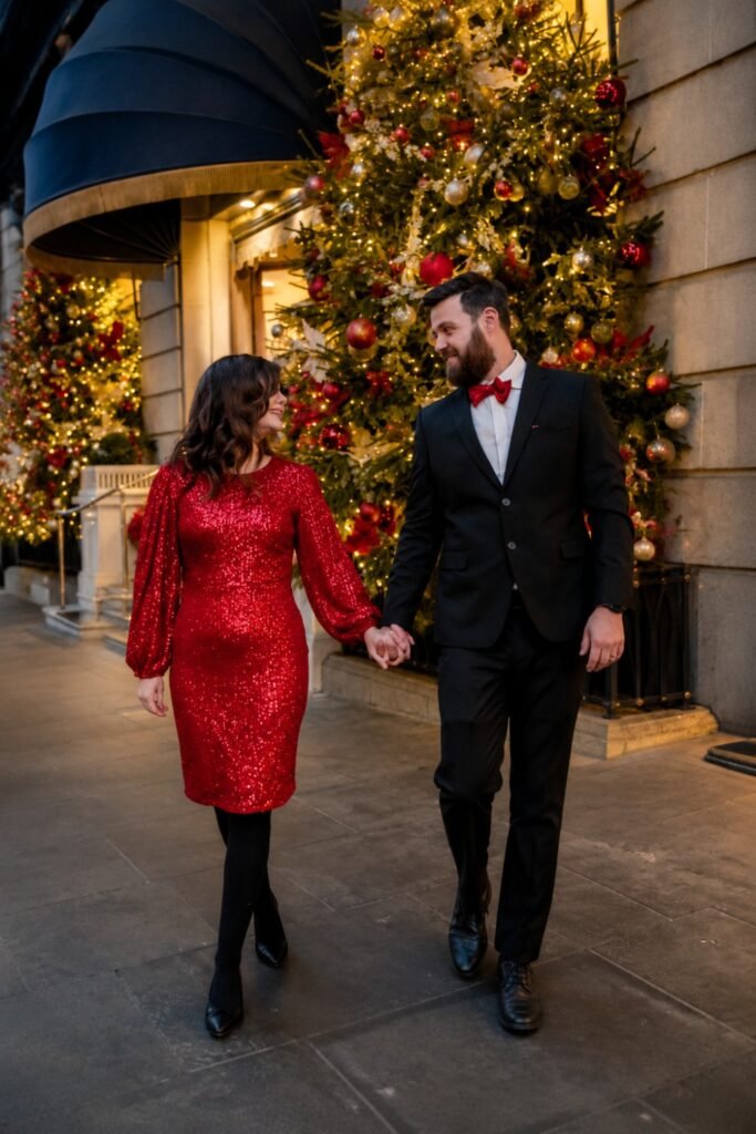 Couple walking in a red dress and dark suit past holiday lights