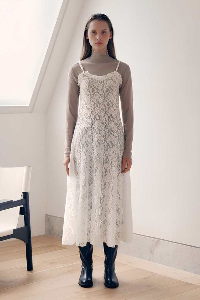 Woman in a white lace midi dress layered over a turtleneck with boots