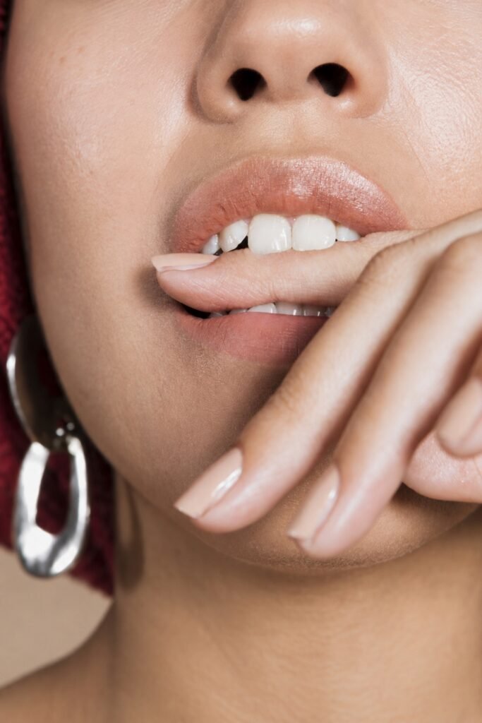 Close-up of nude-berry lips with a fingertip resting on the lower lip