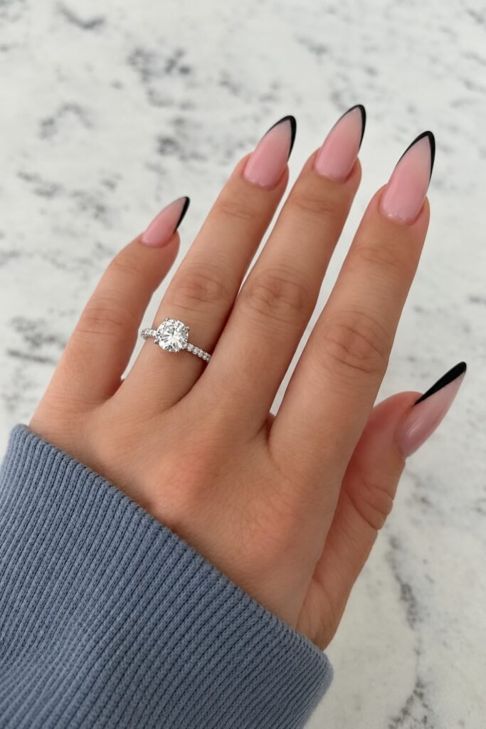 Black micro-French almond nails with an engagement ring