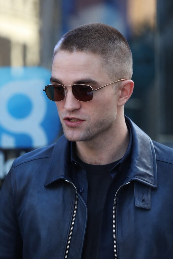 Man with a butch cut wearing sunglasses and a denim jacket