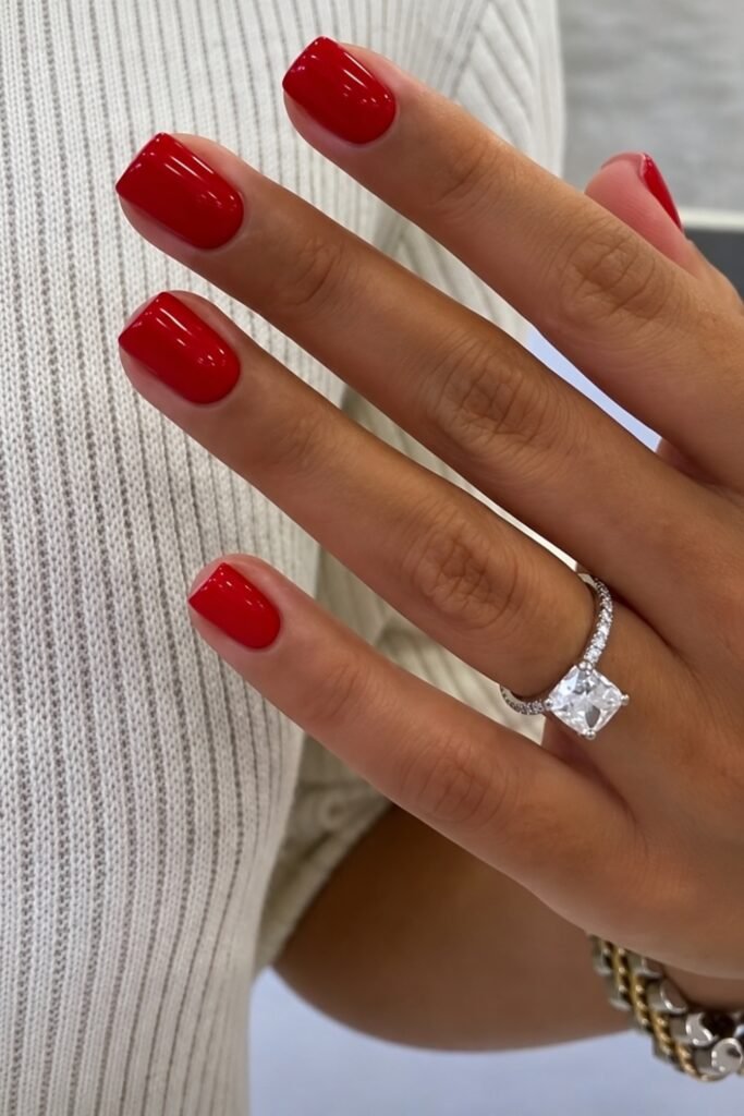 Classic cherry red nails with a diamond engagement ring