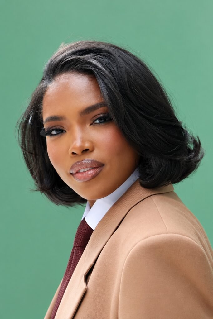 Woman with a classic chin-length black bob and a camel blazer