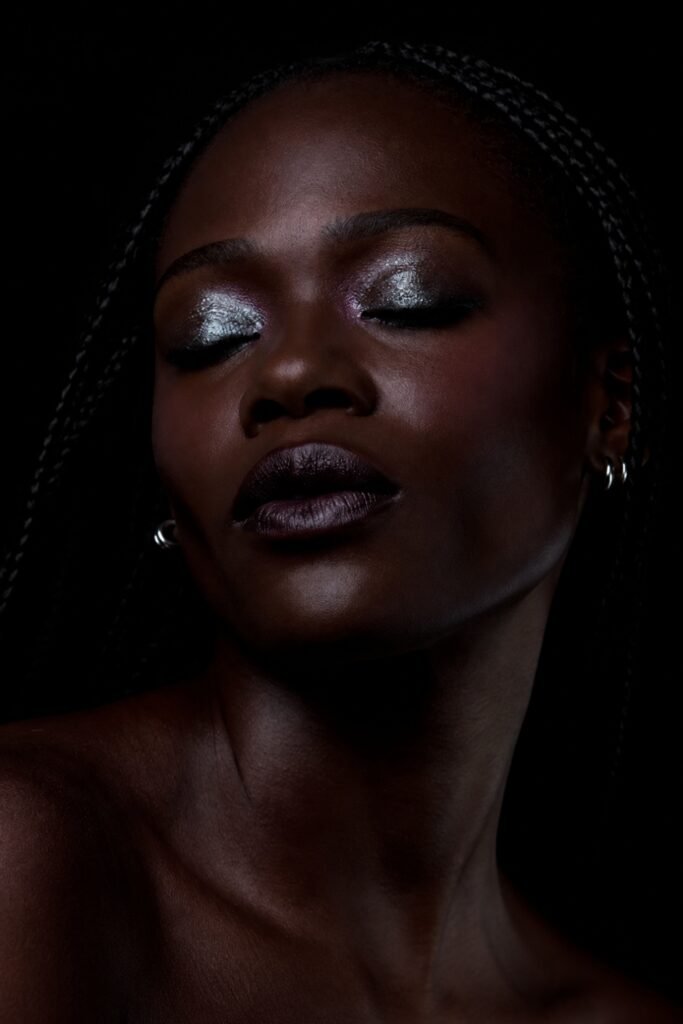 Deep skin with frosted silver eyeshadow against a dark background