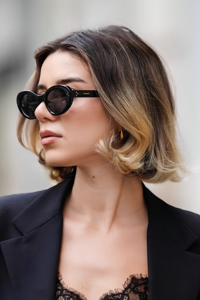 Woman with a grown-out bob, sunglasses and a black blazer