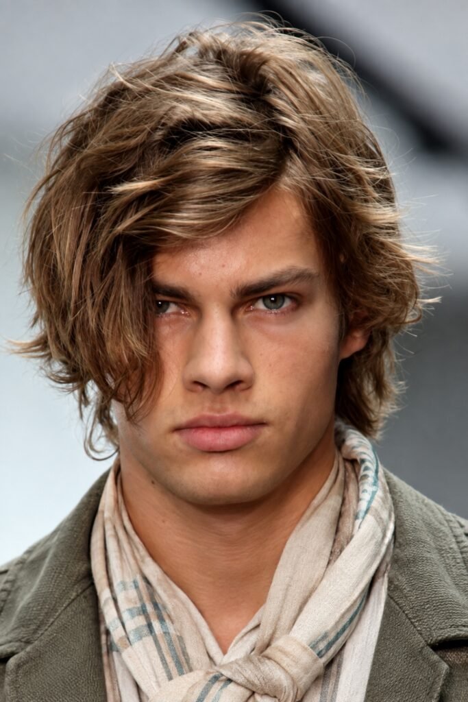 Man with a hockey flow haircut and loose bangs, wearing a scarf