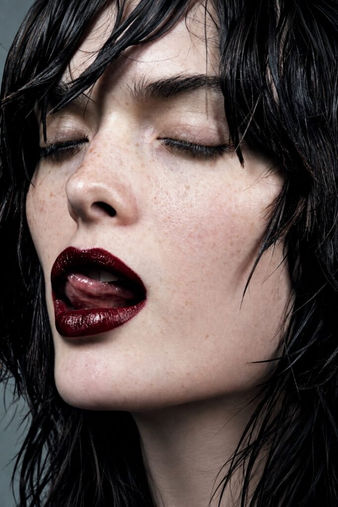 Close-up of glossy dark berry lips and dark tousled hair