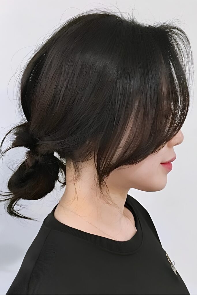 Side view of a low braided bun with curtain bangs