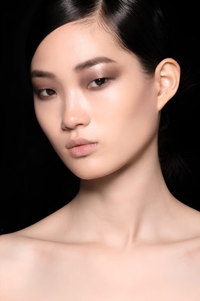 Close-up of soft smoky grey eye makeup with a neutral lip and dark hair