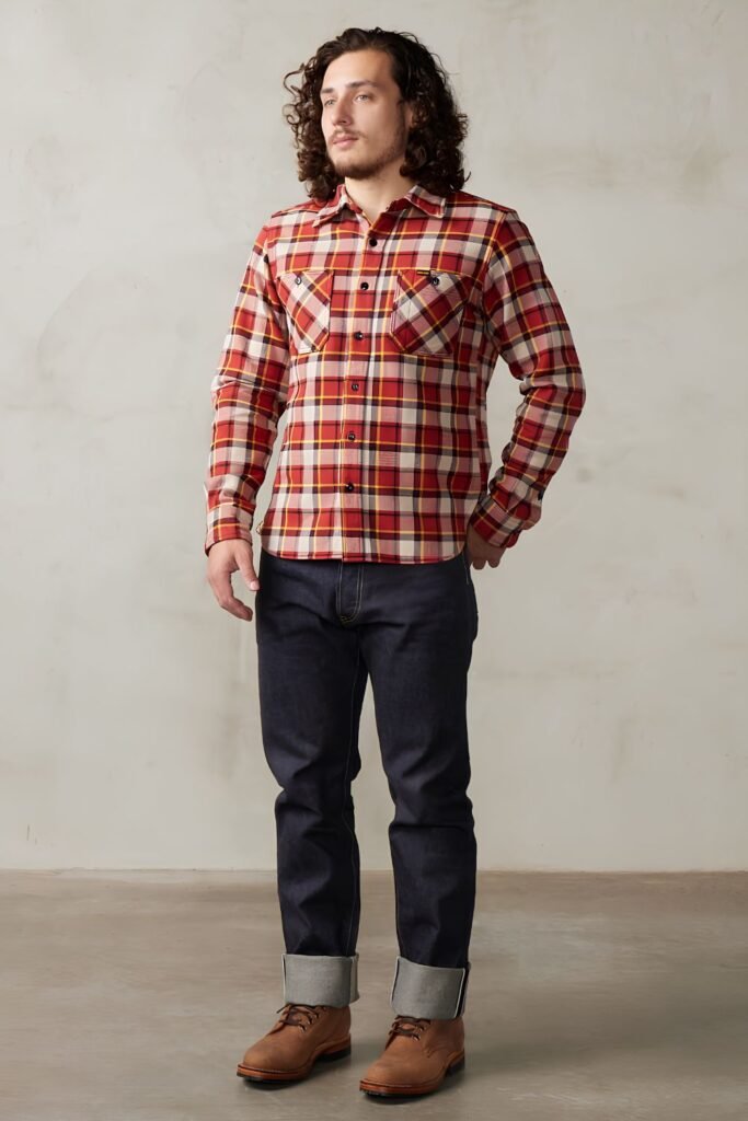 Man in a red plaid flannel shirt with dark jeans and brown boots