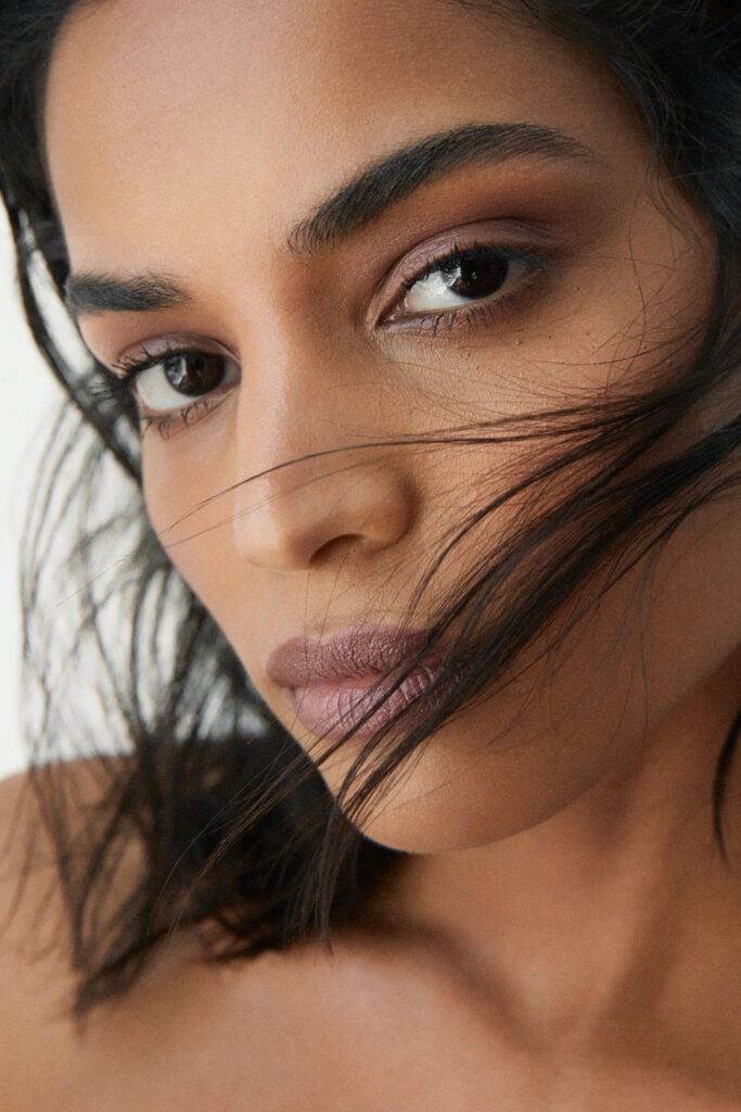 Close-up of soft mauve lips and muted eye makeup with windswept hair