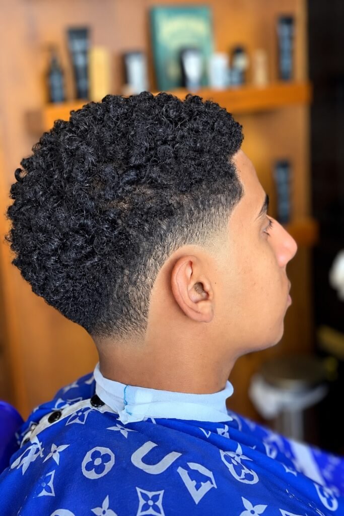 Side view of a short curly taper in a barbershop