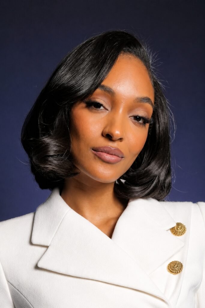 Woman with a glossy black side-parted bob and a white jacket