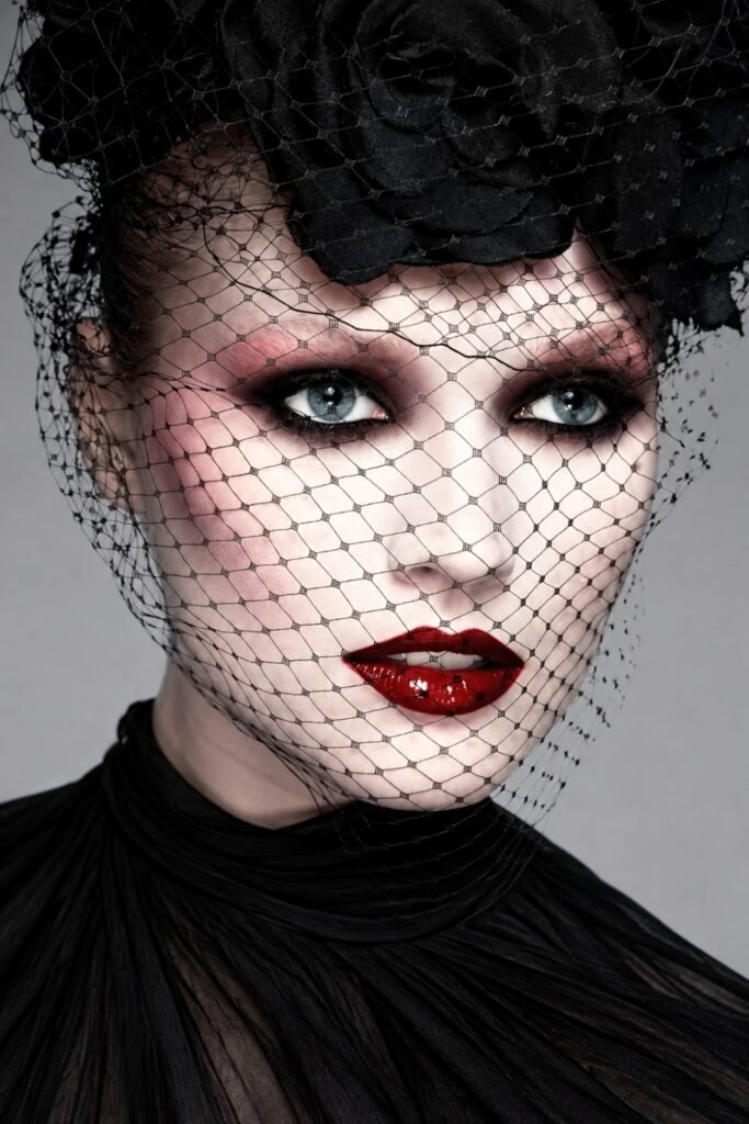 Smoky eyes and dark red lips behind a black dotted net veil