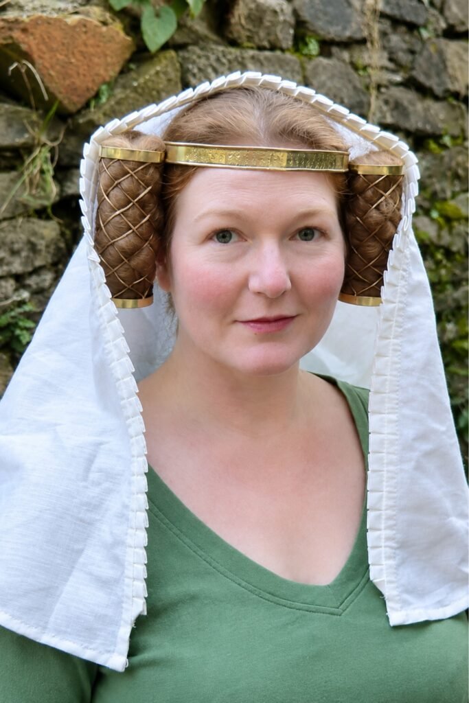 Hair tucked under a white veil with a gold band