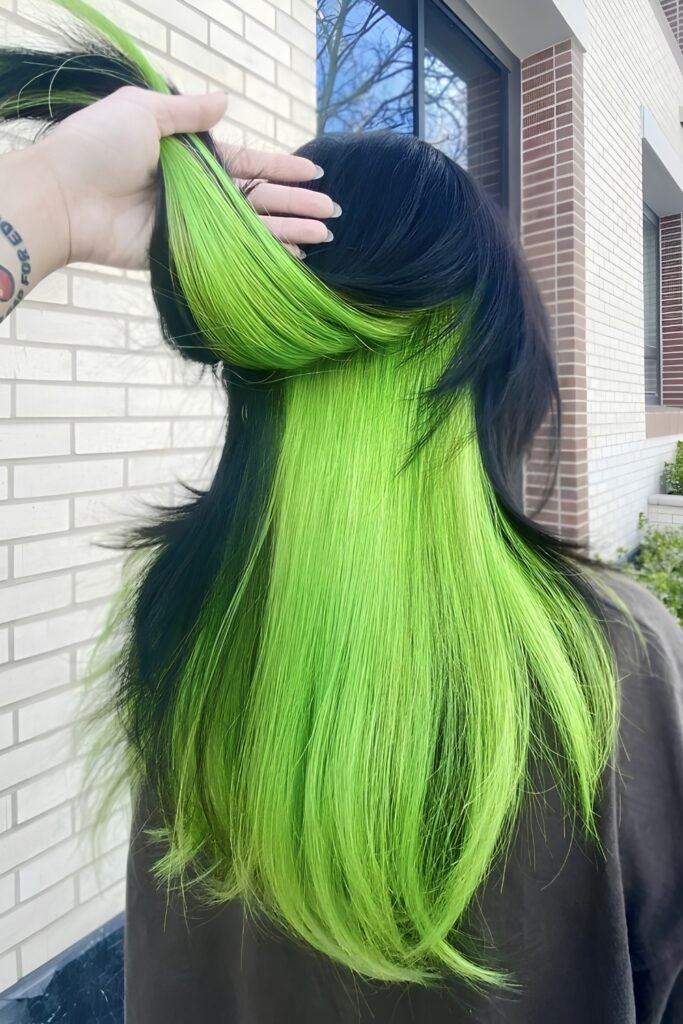 Back view of straight hair with the dark top layer lifted to show neon green underneath