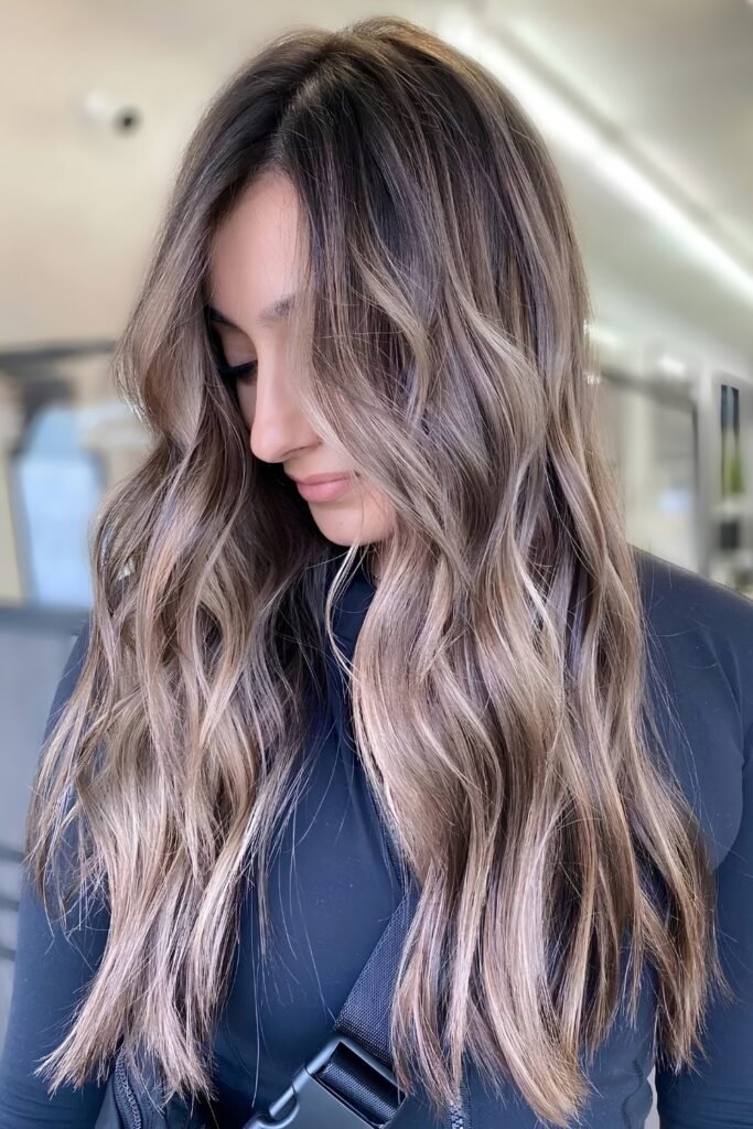 Wavy ash-beige hair with fine babylights and a smudged dark root