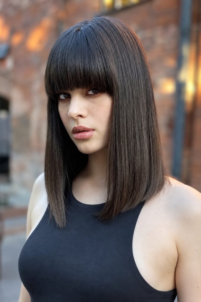 Woman with a dark blunt lob and a full fringe