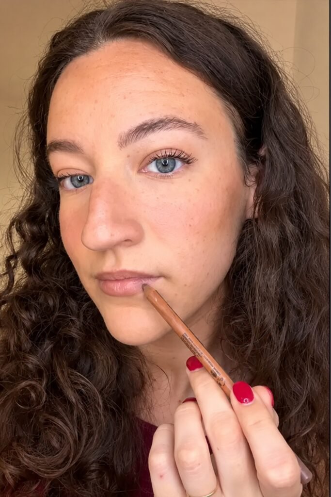 Woman applying brown lip liner in a selfie